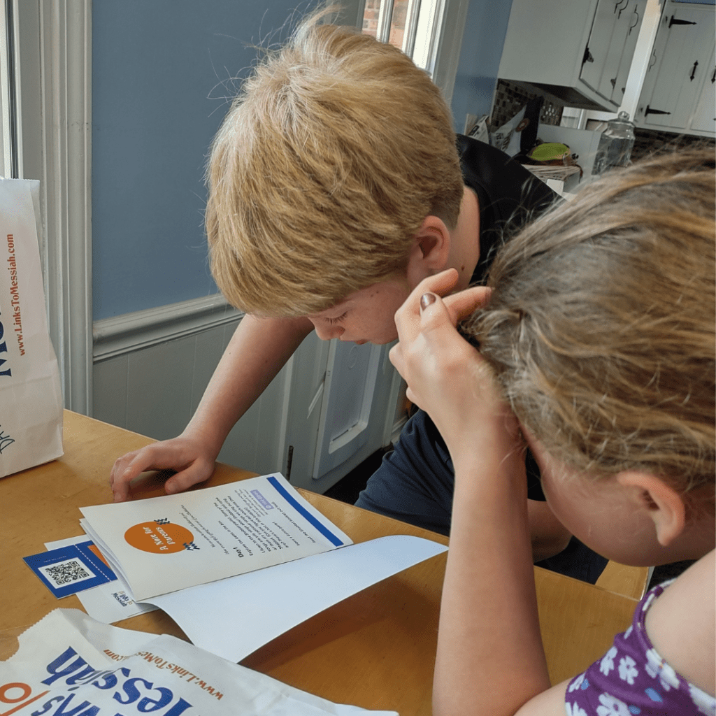 Two kids reading a book from a Links to Messiah Box.