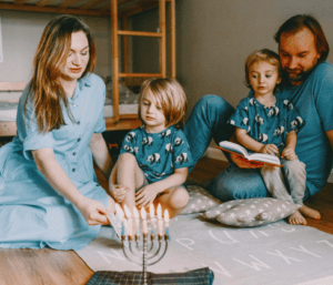 family sitting together celebrating Hanukkah and lighting the menorah